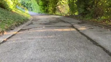 Kırık bir yolun, canlı yeşillikler arasında dolaştığı huzurlu bir manzara, doğa ve açık hava teması için ideal..