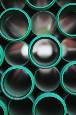 Siyah arka planı olan yeşil borular. Borular öyle bir sıralanmış ki sanki üst üste yığılmış gibiler.