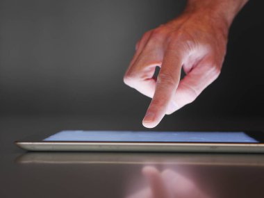 Tablet ekranını işaret eden bir el. Tablet akıllı bir telefon ya da tablettir.