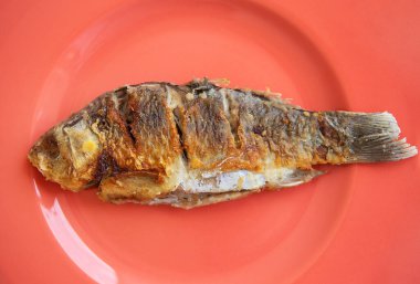 Kızarmış kabuklu sazan balığı, parlak kırmızı bir tabakta servis edilir. Yukarıdan görüntüle