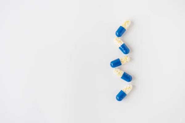 薬カプセル 白い背景に半分青 行に横たわっている フラットレイアウト トップビュー 医療の概念 — ストック写真
