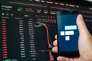 Man holding phone with FTX logo. Global fall of cryptocurrency graph - FTT token fell down on the chart crypto exchanges on app screen. FTX exchange bankruptcy and the collapse depreciation of token clipart