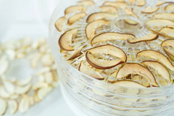 The process of homemade dried fruit or candied fruit in an electric dryer on the table. Fruits for storage and consumption in winter. Apples and pears are already dried in a dryer. Close-up