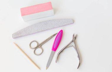 Beyaz bir masada profesyonel manikür seti. El bakımı, kuaför salonu prosedürleri. Dosya, makas, cilt, bambu çubuğu, tırnak uçları.