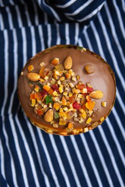 Şekerli meyvelerle süslenmiş bir Paskalya pastası çizgili mavi bir önlüğün üzerinde duruyor. Paskalya dini bayramı kavramı