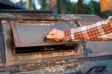 Fırfırlı gömlekli bir adam yeniden kızartılmış et için mükemmel bir profesyonel ızgaraya bakıyor. Profesyonel açık hava mangalı