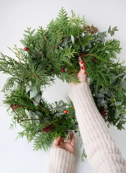 Stylish Christmas wreath for the interior, hang the wreath on the door. Handmade, the girl holds a freshly made wreath in her hands. The atmosphere of the holiday, Christmas and New Year