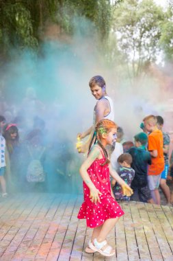 Lviv, Ukrayna - 18 Temmuz 2021: Renkli Holi Festivali, yetişkin ve küçük çocuklardan oluşan bir kalabalık renkli boya atıyor. Kızılderili tatili, çocuklar tahta sahnede koşuyor.