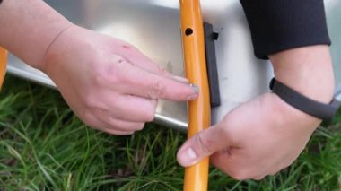 Man screwing a nut onto a bolt with a washer and tightening it by hand. Male hands collects a garden wheelbarrow - aluminum pipe is screwed to the iron base with a bolt, nut and washers close-up view