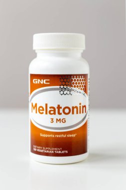 Kyiv, Ukraine - 27 January 2022: Jar of Melatonin capsules from GNC. 3 mg tablet to improve sleep and fight insomnia - nutritional supplement and medicine for men and women. Shallow depth of field