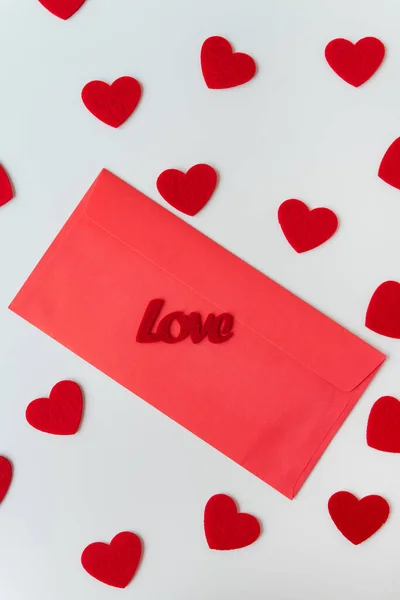 A love letter, the inscription of love on a red paper envelope on the background of small red hearts. The concept of St. Valentine's Day