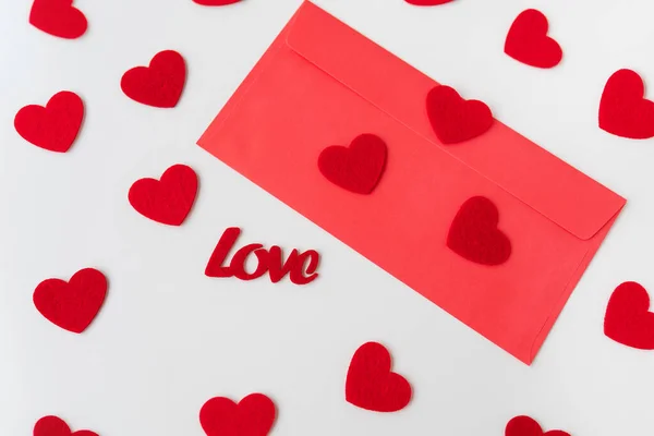 A love letter, the inscription of love on a red paper envelope on the background of small red hearts. The concept of St. Valentine\'s Day