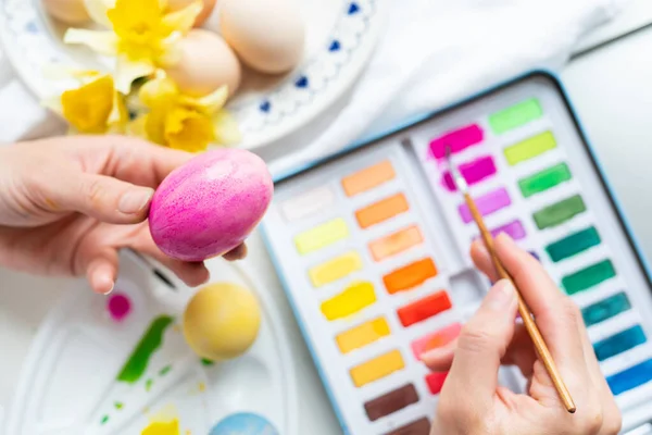 A brush in the process of painting Easter eggs with watercolors. The concept of preparing for Easter. View from above