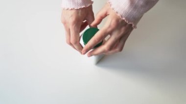 Kapanış kızı elleri kapalı bir tıbbi kapsül kavanozunu açıyor. Kadın kepini söker, koruyucu zarını yırtar ve spor haplarını avucuna döker. Sağlık hizmeti, sağlıklı yaşam tarzı konsepti