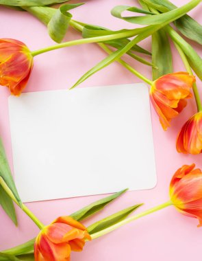 Güzel bir buket turuncu şakayık lalesi ve ortasında pembe arka planda izole edilmiş beyaz bir kart. Dikey fotoğraf. Tasarımcılar için Reddy düzeni, düzen