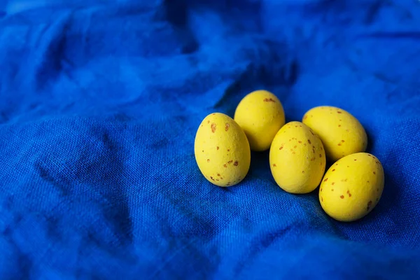 蓝色纹理亚麻布背景的餐巾上装饰着黄色复活节彩蛋的顶部视图 复活节概念 登记地点 — 图库照片