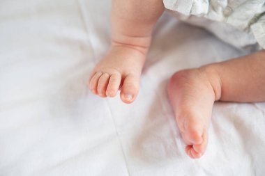Yeni doğmuş bir bebeğin küçük ayakları yatağın üstünde, manzaralı. Annelik kavramı, emzirme.