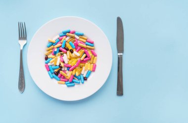 Tabletler, kapsüller, vitaminler ve mavi zemin üzerinde beyaz bir tabakta doğal organik gıda takviyeleri. Minimum modern eczane ya da sağlık hizmeti kavramı