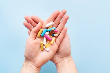 Kız avuçlarında parlak renkli vitaminler, besin takviyeleri ve ilaçlar tutuyor. Tıp ve sağlık desteği kavramı