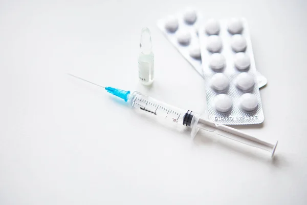 stock image Preparation for vaccination against covid-19. Syringe, vaccine, pills, medical mask on a white table