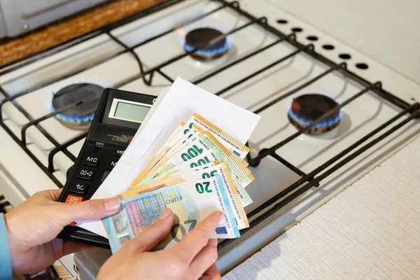 Payment of utility bills, calculations on a calculator. Euro and dollar bills lie near a burning gas burner. The concept of increasing the cost of natural gas supply and payment. Energy crisis, top view
