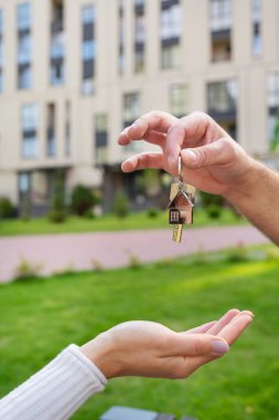 Yeni bir evden ya da genç bir ailenin elinde daireden alınmış metal bir ev şeklinde anahtarlık. Bir ev almanın mutluluğu. Emlakçıdan anahtarları teslim ediyorum.