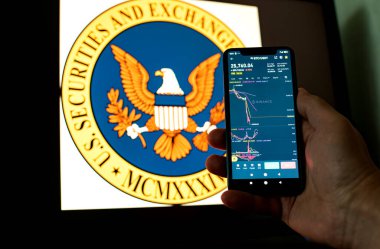 Kyiv, Ukrayna - 06 Haziran 2023: Adam, arka planda SEC logosuna karşılık Binance üzerine Bitcoin grafiği düşen bir akıllı telefon tutuyor. S.E.C. Düzenleyicilere Yanlış Yönlendirme Fonları ve Yalan Söylemekle Suçlanıyor