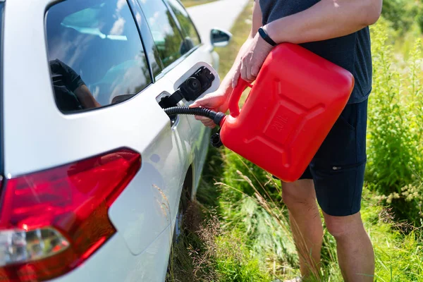不可抗力 路上的问题 路上冒险 燃料问题 司机从路边的一个红色罐子里装满了汽车的空油箱 — 图库照片#