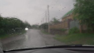 Yağmur mevsiminde yol kenarına park edilmiş arabanın içindeki hareket silecekler. Sağanaktan dolayı ön cama yağmur damlaları damlıyor. Yağmur damlasını temizlemek için silecek süpürüp camı akıtmak
