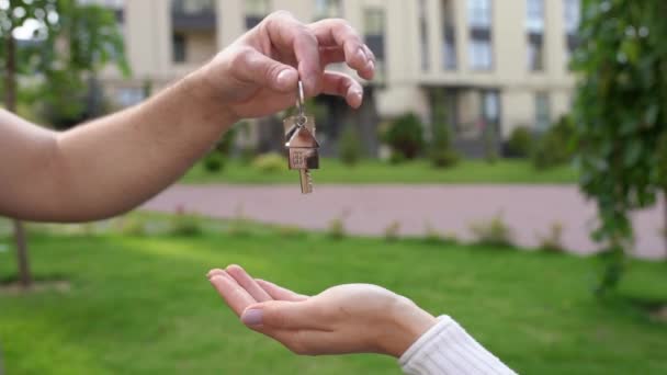 在一个新的社区买房子 男地产经纪人拿着新房的钥匙 钥匙落在女买家的掌心 动作缓慢 购买和销售房地产 丈夫给妻子一套公寓 — 图库视频影像