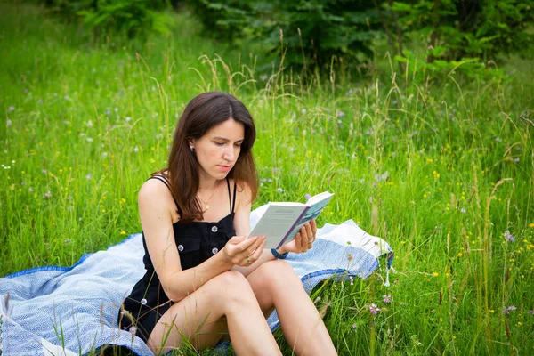 屋外ピクニック 青い遊びに座っている間に少女は開いた空気中の本を読む 少女は新鮮な空気を楽しんでいる 屋外レクリエーション — ストック写真