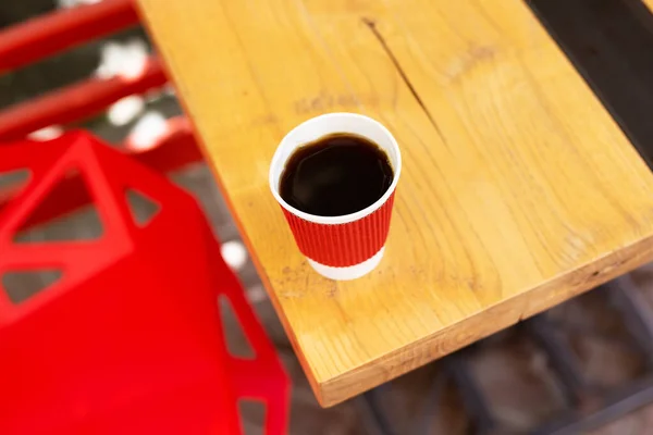 Een Houten Tafel Waarop Een Rode Plastic Beker Met Koffie — Stockfoto
