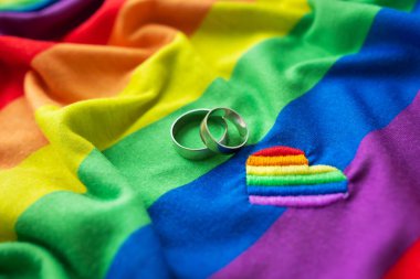Bir lgbt gökkuşağı bayrağında iki alyans ve işlemeli bir kalp. homoseksüel evlilik. LGBT hakları ve hukuk. Gezegendeki tüm insanlar için eşit haklar.