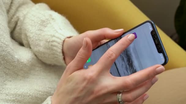 Młoda Kobieta Siedzi Krześle Trzymając Smartfona Uruchamia Aplikację Instagram Przewijanie — Wideo stockowe