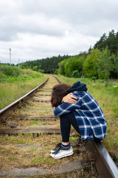 stock image Stress, sadness, loneliness, pain. An upset girl sits on the rails, a psychological situation, help and support. Vertical photo