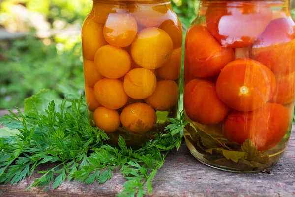 stock image Tomatoes yellow and red in a jar, the process of harvesting for the winter. Close-up, jars outside on a wooden chair