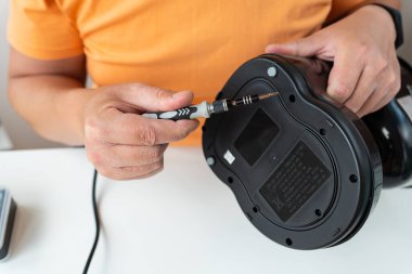 Bir adam masaya oturur ve tornavidayla küçük bir kahve makinesini tamir eder. Yakın plan.