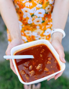 Bograch, borş, pancar ve etli baharatlı çorba, yakın plan. Kız pancar çorbasını tabakta tutuyor.