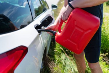 Şoför, yolun kenarındaki kırmızı bir kutudan arabanın boş deposunu dolduruyor.