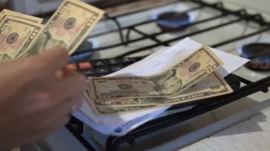 Bir kadının elleri parayı sayar ve yanan ocakla birlikte bir gaz ocağına koyar. Faturaları ödemek ve ödemeleri yapmak. Arz maliyeti, doğal gaz için ödeme. Enerji krizi. Yüksek maliyet, benzin fiyatı