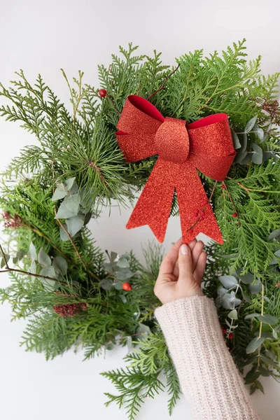 İç mekan için şık bir Noel çelengi, kapıya çelenk asın. El yapımı, kız elinde güzel kırmızı bir fiyonklu yeni yapılmış bir çelenk tutuyor. Şenlikli atmosfer