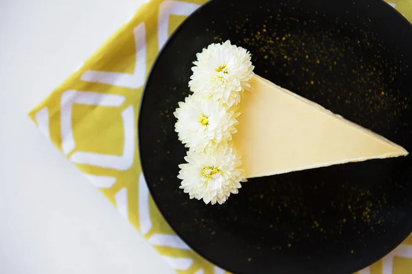 奶油芝士蛋糕 白色的花装饰在黄色的餐巾上 — 图库照片
