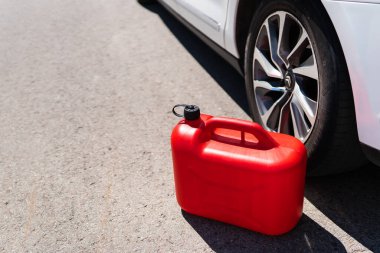 Kırmızı plastik bir kutu yolun ortasında, beyaz bir arabanın yanında. Yakıt ikmali sorunları