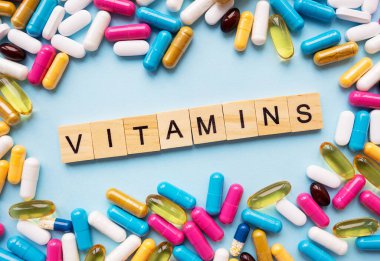 Sağlık ve tıp konsepti. Farklı semptomlar için farklı renkli haplar, ortada - tahta harflerle yazılmış vitaminler.