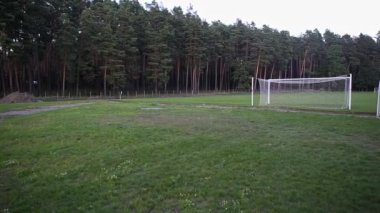 Bir çam ormanının ortasında lise futbol sahası ve konut binaları. Güzel bir manzara. Futbol sahasında gol ve duruş - panorama. 4K 'deki futbol stadyumunun panoramik görüntüsü