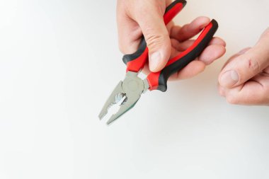 Beyaz arka planda kırmızı ve siyah penseyi sıkıca kavrayan bir el.