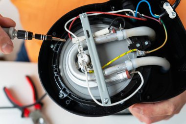 Bir hoparlörü, karmaşık kabloları ve görünen bileşenleri tamir eden ellerin yakın çekimi