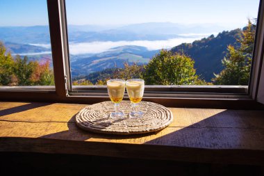 Dağlara bakan açık bir pencerenin yanında sıcak bir içecek duruyor. Pilipets, Ukrayna.