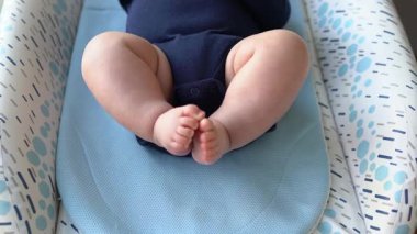 Bebek bacakları masa değişiminde, anne bebek bezi ıslatma göstergesini kontrol ediyor. Yakın çekim, üst görünüm.