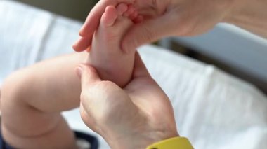 Yumuşak dokunuş. Anne bebek ayağına krem sürüp masaj yapıyor. Bacak, cilt bakımı, yakın plan..